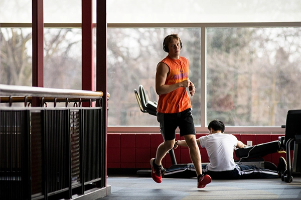 One student running track another stretching