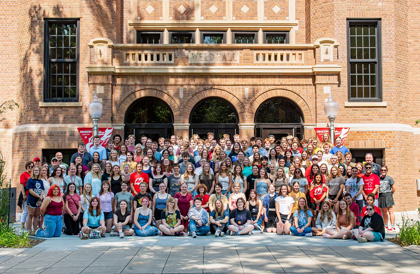 Dozens of students pose for a photo in front of Weld Hall