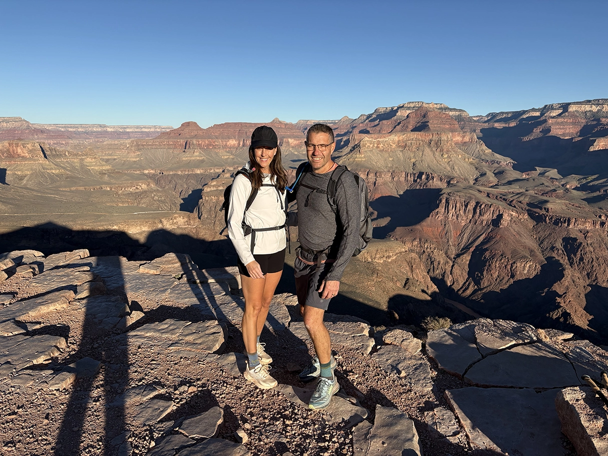 Sandy and her husband stand at the top of the Grand Canyon